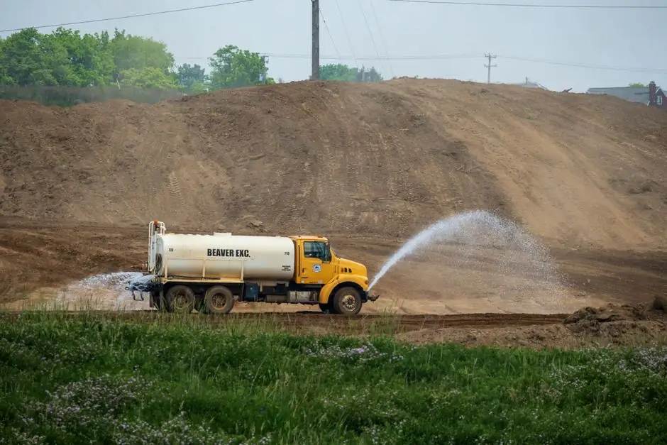Yellow water tanker sprinkling soil at a construction site in Canton, Ohio.